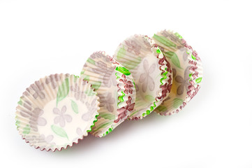 Paper, disposable muffin baking dish with a delicate floral pattern, shot on a white background