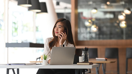 Young businesswoman calling her phone in modern office.