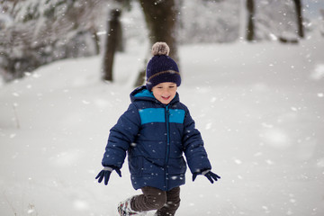 Fototapeta na wymiar Adorable, cute boy playing with snow cheerfully. Wintertime, kids activity
