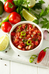 Traditional mexican homemade salsa sauce and ingredients on a white wooden table. Top view on a flat background. Copy space.