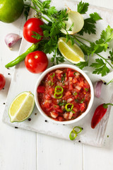 Traditional mexican homemade salsa sauce and ingredients on a white wooden table. Top view on a flat background. Copy space.