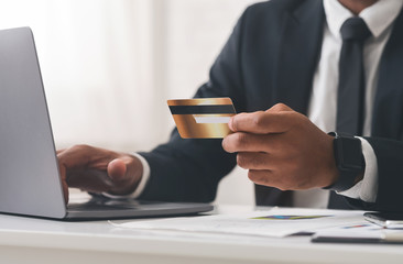 Cropped photo of businessman using laptop and holding credit card