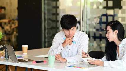 Young professional designer team with tablet discussing the idea together in modern office room.