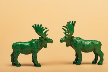 Obraz premium Green toy moose on yellow background, hunting for horns concept