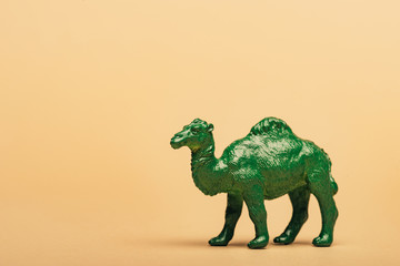 Green toy camel on yellow background, animal welfare concept