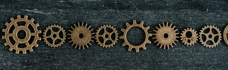 flat lay with vintage metal gears on dark wooden background, panoramic shot