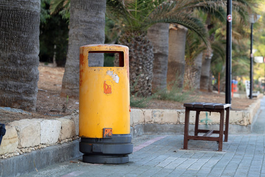 Colorful trashcan and bench located near the beaches of Cyprus near Limassol. In this photo there is also some palm trees. Color image during sunny and warm summer afternoon. No people.
