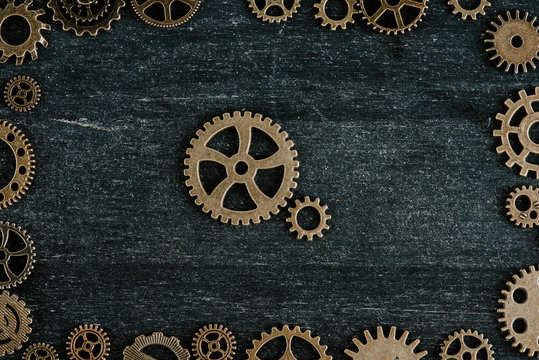 top view of vintage metal gears in frame on dark wooden background © LIGHTFIELD STUDIOS