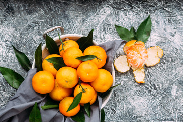  Ripe tangerines in a plate on a gray table