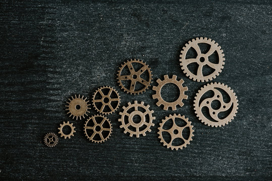 top view of retro metal gears on dark wooden background © LIGHTFIELD STUDIOS