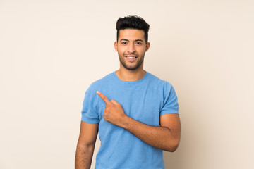 Young handsome man over isolated background pointing to the side to present a product