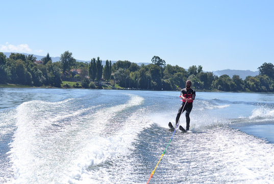 Young man water skiing over the river in summer, having fun