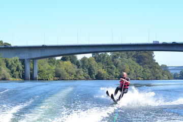 Young man water skiing over the river in summer, having fun