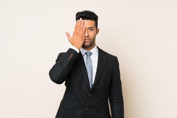Young handsome businessman man over isolated background covering a eye by hand