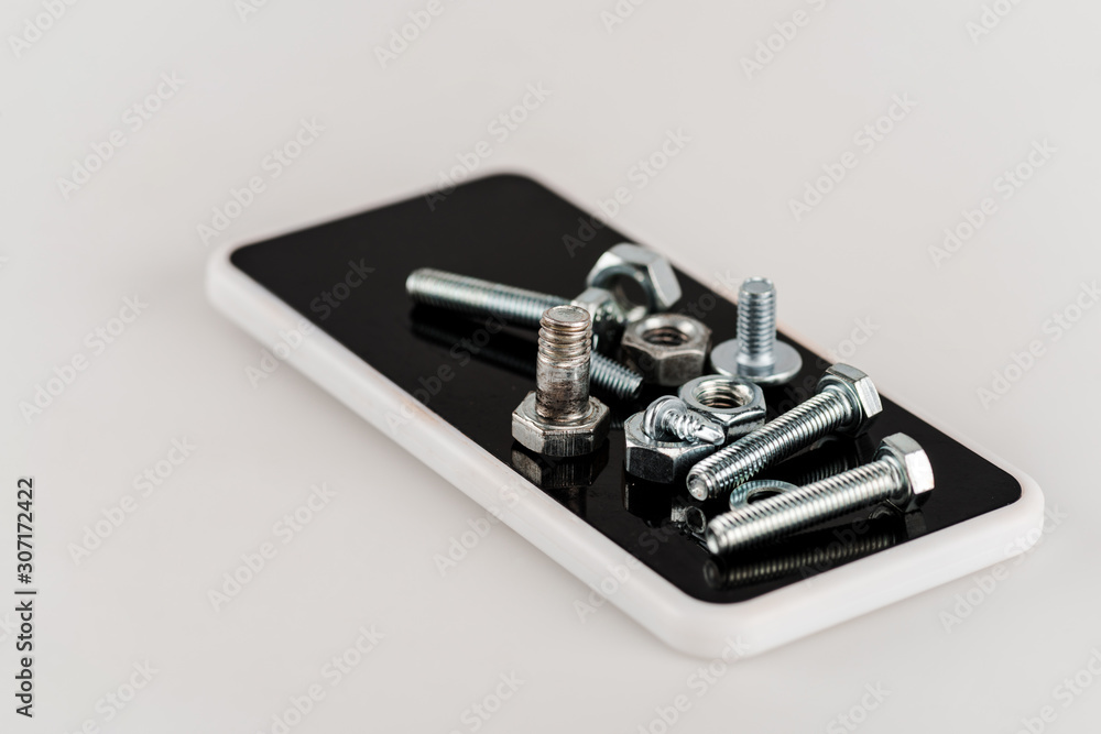 Sticker metal screws and bolts on smartphone on white background