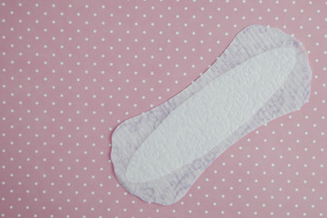 white thin feminine sanitary pad for every day on a pink polka dot background 