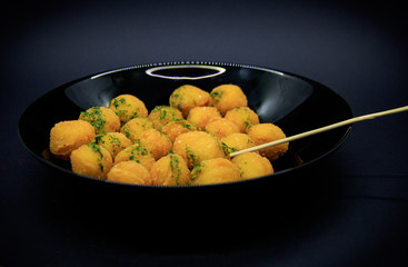 Potato balls in a black plate on a dark background