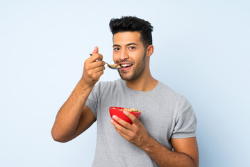 Young handsome man over isolated background holding a bowl of cereals