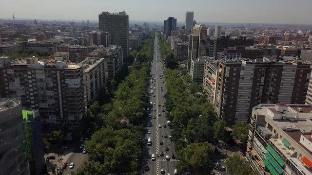 Aerial descending shot above Paseo de la Castellana in Madrid with dense traffic.