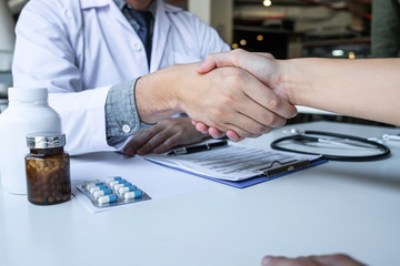 Doctor and patient shaking hands after a good and successful treatment in the hospital, healthcare...