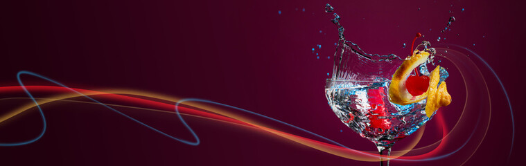 Colorful cocktail in glass with splashes garnished with lemon and cherries.