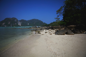 Stone beach, blue sea and mountains. Summer sunny day. Phi-Phi island Thailand.
