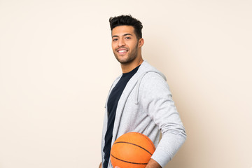 Young handsome man over isolated background with ball of basketball