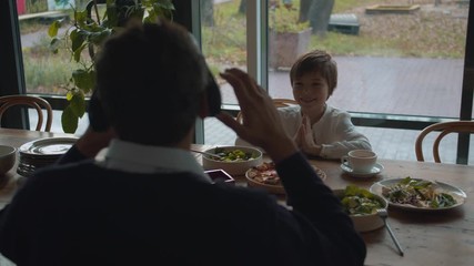 Father puts on a virtual reality glasses at lunch with son - Powered by Adobe