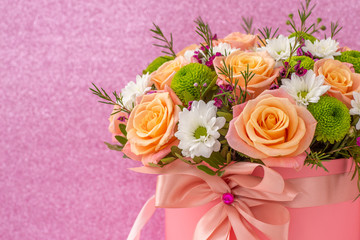Obraz na płótnie Canvas Beautiful bouquet in a coral luxury present box with a pink bow, isolated on pink background