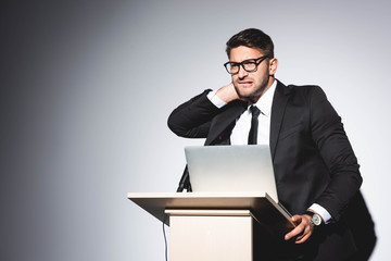 scared businessman in suit standing at podium tribune and looking away during conference on white background