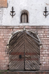 Fototapeta na wymiar Portal in an old stone wall. Wooden door. Window and anchors, Riga.