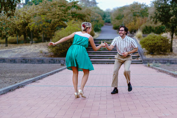 Couple dancing swing lindy-hop in outdoor in the park. People having fun dancing vintage music together in the nature.
