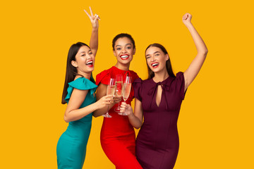 Three Models Clinking Glasses Having Fun Standing Over Yellow Background