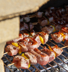 Meat and sausages skewers cooking on a grill