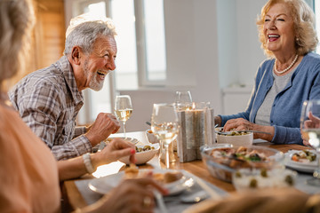 Cheerful senior man having fun during a lunch with his friends at home.