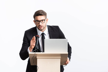 businessman in suit standing at podium tribune and pointing with finger during conference isolated...