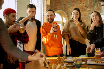 Happy co-workers celebrating while company party and corporate event. Young caucasian people in casual clothes drinking, laughting. Concept of office culture, teamwork, friendship, weekend. Having fun