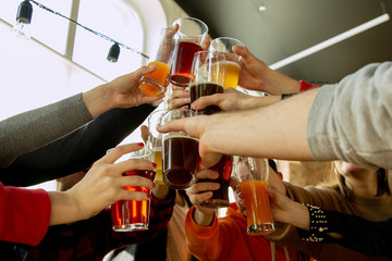 Happy co-workers celebrating while company party and corporate event. Young caucasian people in casual clothes drinking, close up, having fun. Concept of office culture, teamwork, friendship. Cheers.