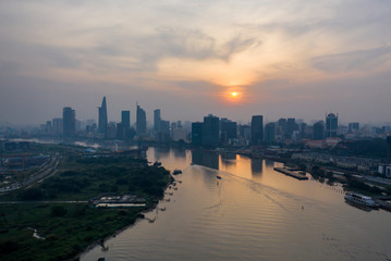 Saigon river sunset with extreme air pollution. Beautiful orange, red sky and reflections with Ho Chi Minh City, Vietnam Skyline. © Paul