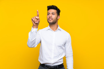 Young handsome man over isolated yellow background touching on transparent screen - obrazy, fototapety, plakaty