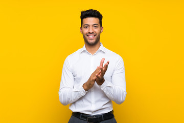 Young handsome man over isolated yellow background applauding