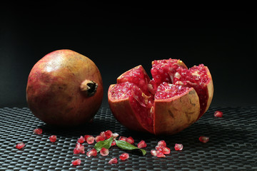 Pomegranate with grains and seeds on dark background