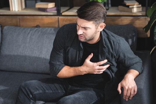 handsome man in shirt having heart attack in apartment