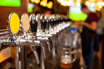 Lot of vintage Golden beer taps in the bar with the bartender in the background