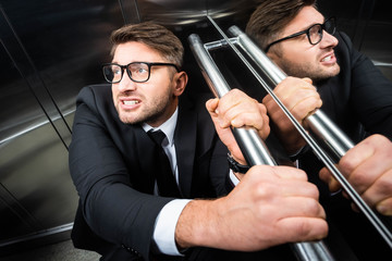 high angle view of scared businessman in suit with claustrophobia in elevator - obrazy, fototapety, plakaty