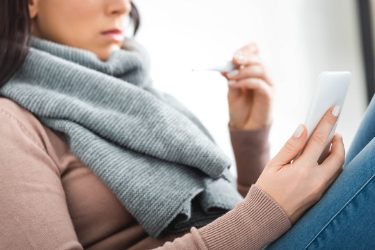 Cropped View Of Ill Woman With Thermometer Having Online Consultation With Doctor On Smartphone