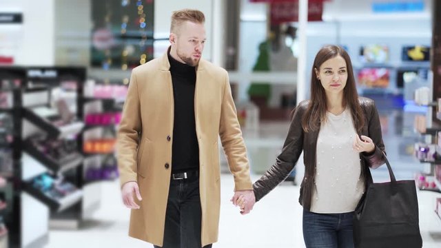 Man and woman walk around mall holding hands and talk, steadicam shot
