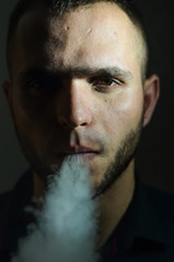 Man Vaping an Electronic Cigarette. Vaper Hipster Smoke Vaporizer and Exhals Smoke Cloud.