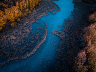 Aerial view of frozen river - sunrise first light on tree tops - rural Lithuania during first winter season days