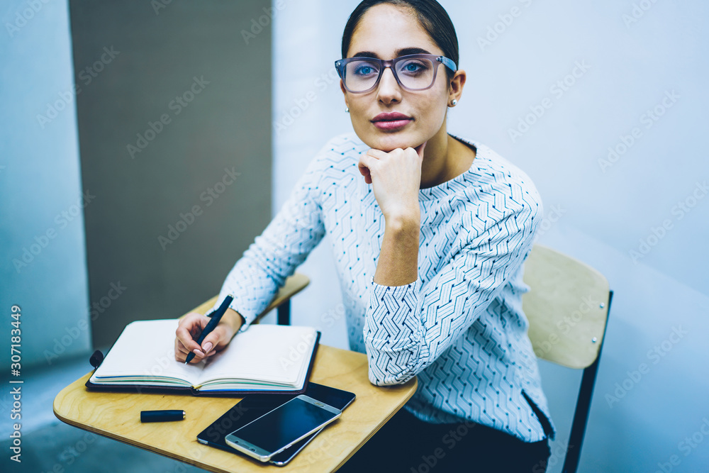 Aufkleber pensive young woman sitting at desk with notepad studying at language school for improve skills and 